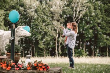 Mutter und Baby bestaunen Seifenblasen auf der Wiese