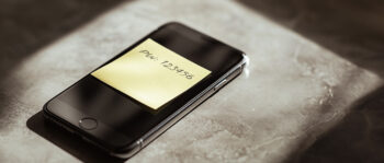 Dunkles Smartphone mit gelbem Post-it auf dem